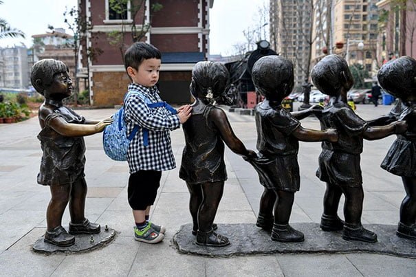 adorable innocent child gets in line with statues
