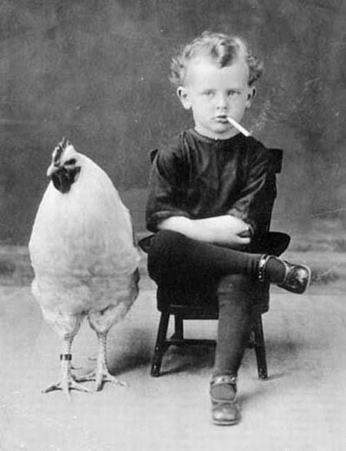 old black and white photo of child smoking and rooster