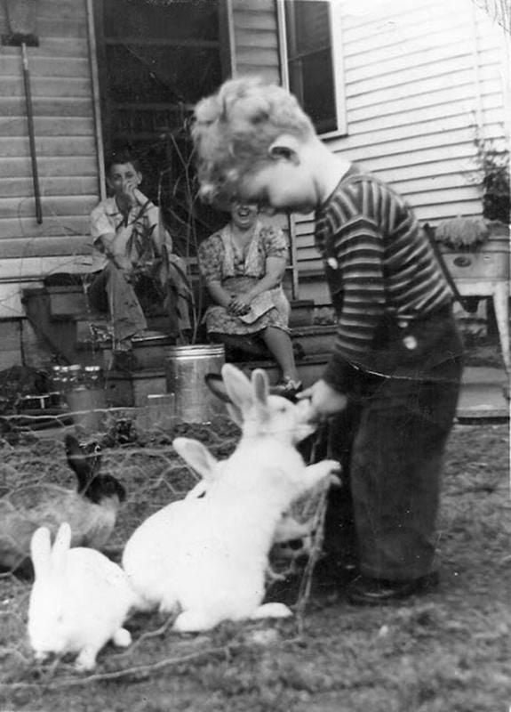 old black and white photo of child and pet rabbits