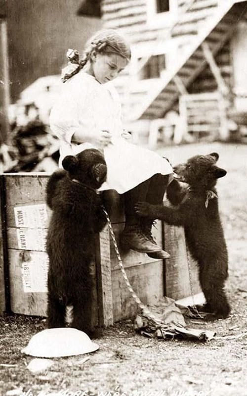 old black and white photo of child and pet bear cubs